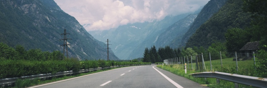 Road along the trees and mountains with cloudy weather